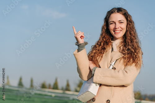 Carefree smiling woman pointing finger up in the air. Pointing Skyward.