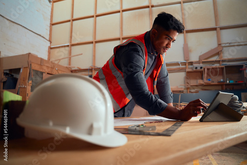 Foto Young man writing with digitized pen on digital tablet next to safety helmet in