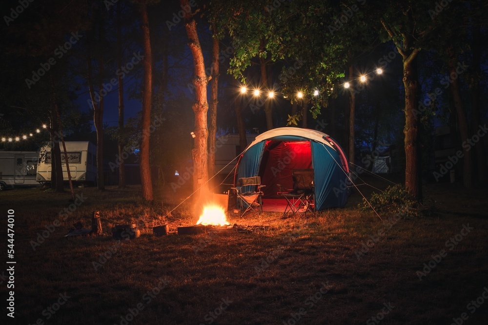 Atmospheric night adventure. Tent with a midnight fire in the forest.