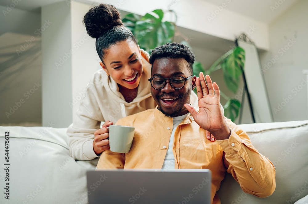 Multiracial couple using laptop while sitting on a sofa at home