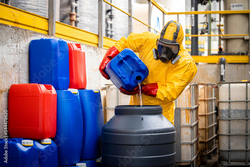 Chemical worker or technologist in yellow protection suit and gas mask making sulfuric acid for industry. photo