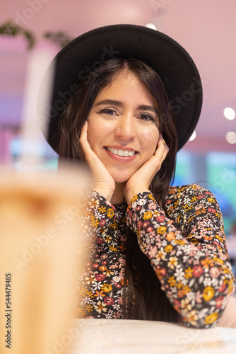 adorable young woman looking at camera and smiling, wearing trendy hat, natural beauty with details on face with long hair, lifestyle