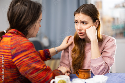 Young caucasian woman feeling upset. Her friend helping and consoling her. photo