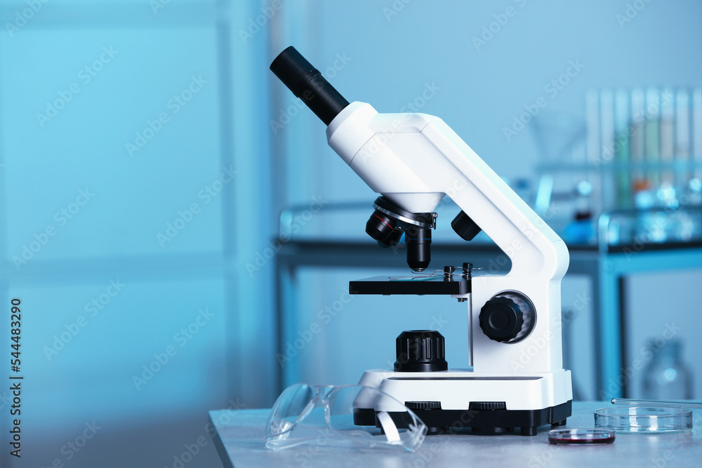 Modern medical microscope on gray table in laboratory, space for text Modern medical microscope on gray table in laboratory, space for text