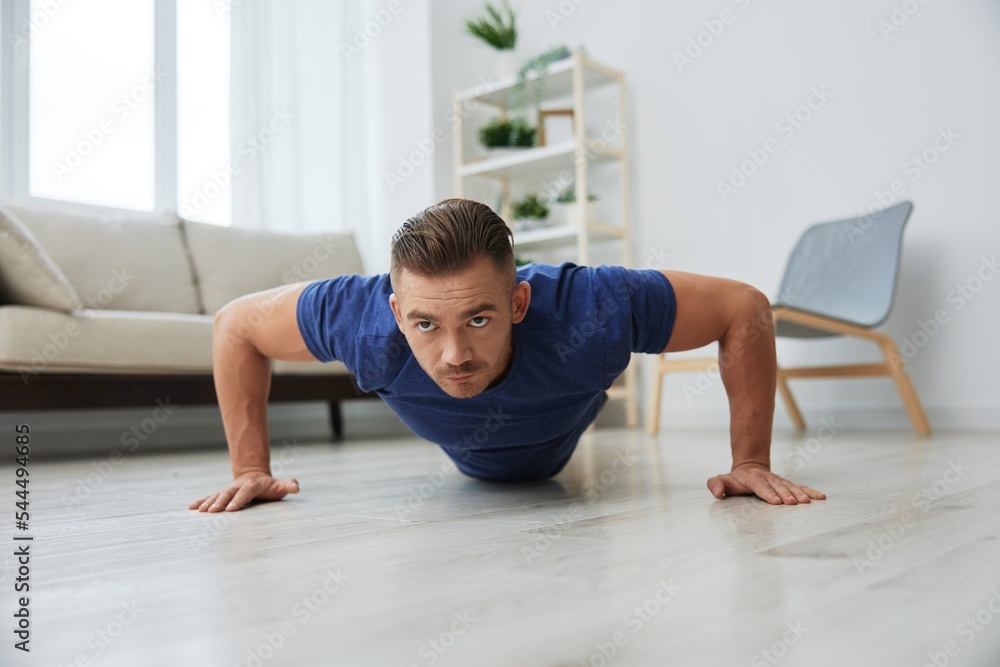 Man sportsman training at home, push-up exercises for arm, leg and back muscles, strong body and correct posture, the concept of health and beauty Man sportsman training at home, push-up exercises for arm, leg and back muscles, strong body and correct posture, the concept of health and beauty