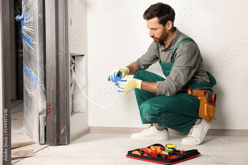 Fotografia Electrician fixing wires with insulating tape indoors