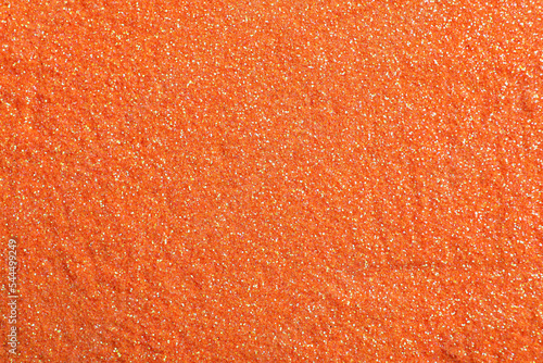 Shiny orange glitter as background, top view