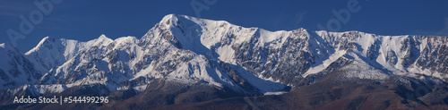 Snow-capped mountain peaks, contrasting morning light, large panorama © Valerii