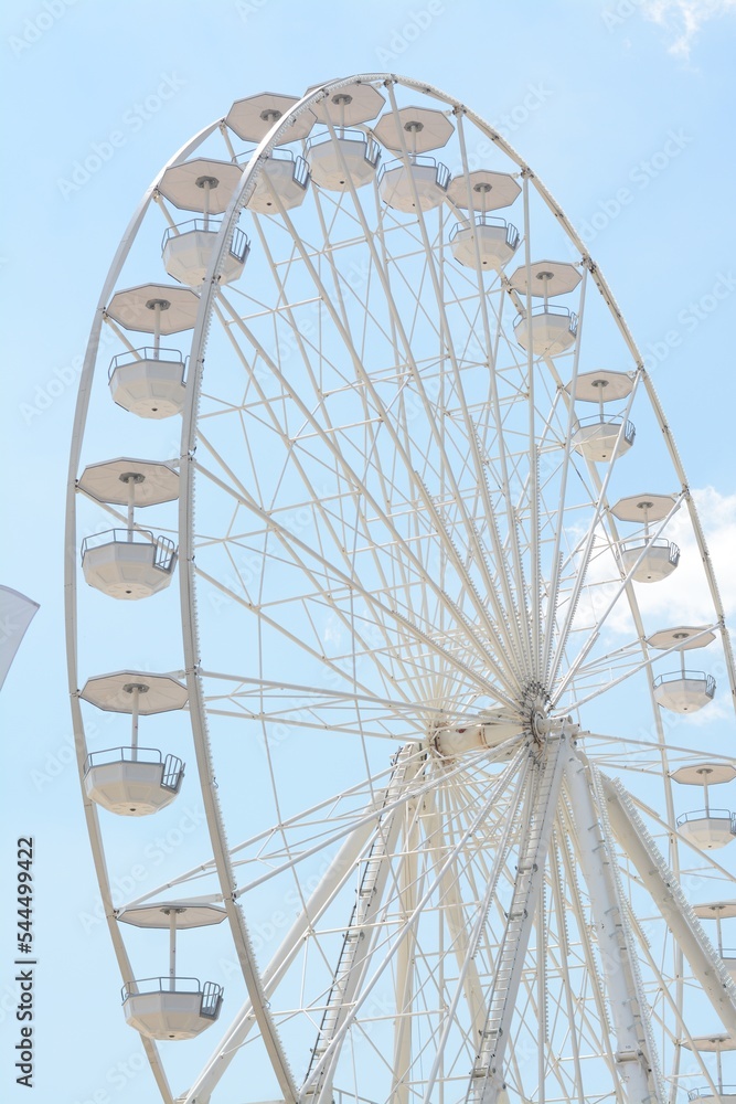 Large white observation wheel against blue cloudy sky, low angle view