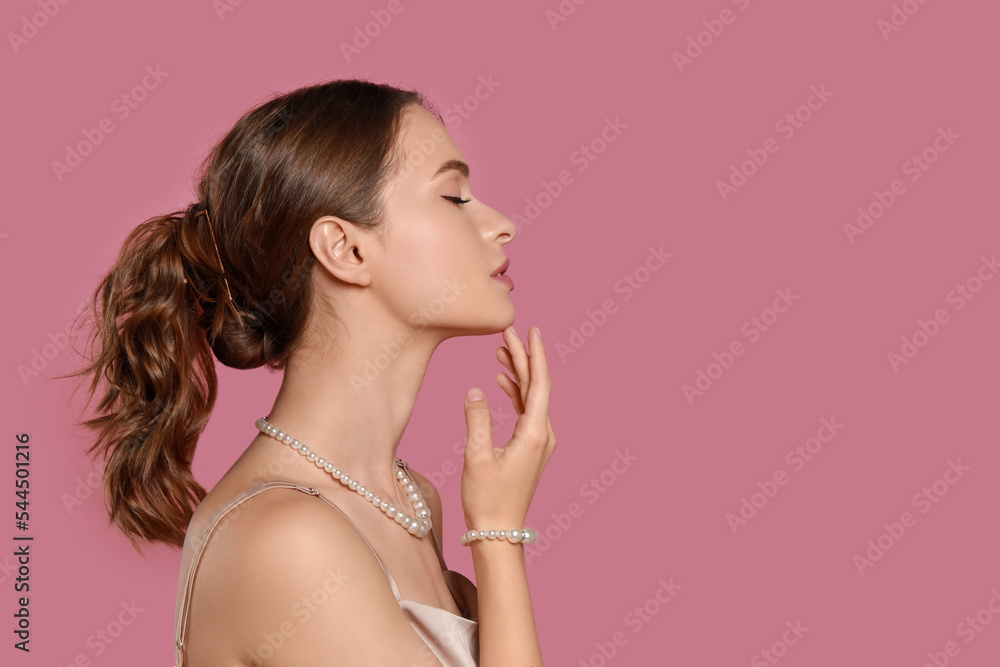 Young woman wearing elegant pearl jewelry on pink background, space for text Young woman wearing elegant pearl jewelry on pink background, space for text