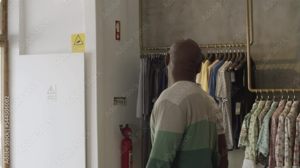 Romantic black gay couple leaving clothing store together, kissing and holding hands. Happy customers waving goodbye after making purchase. Tracking shot. Shopping, LGBT, romance concept. Romantic black gay couple leaving clothing store together, kissing and holding hands. Happy customers waving goodbye after making purchase. Tracking shot. Shopping, LGBT, romance concept.