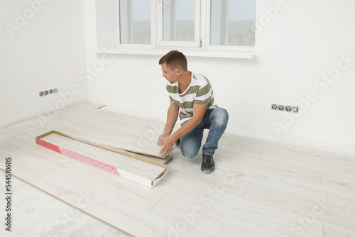 Professional worker installing new laminate flooring indoors © New Africa