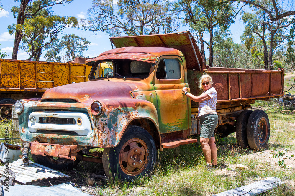 Blonde woman opening door of abandoned opal mining truck