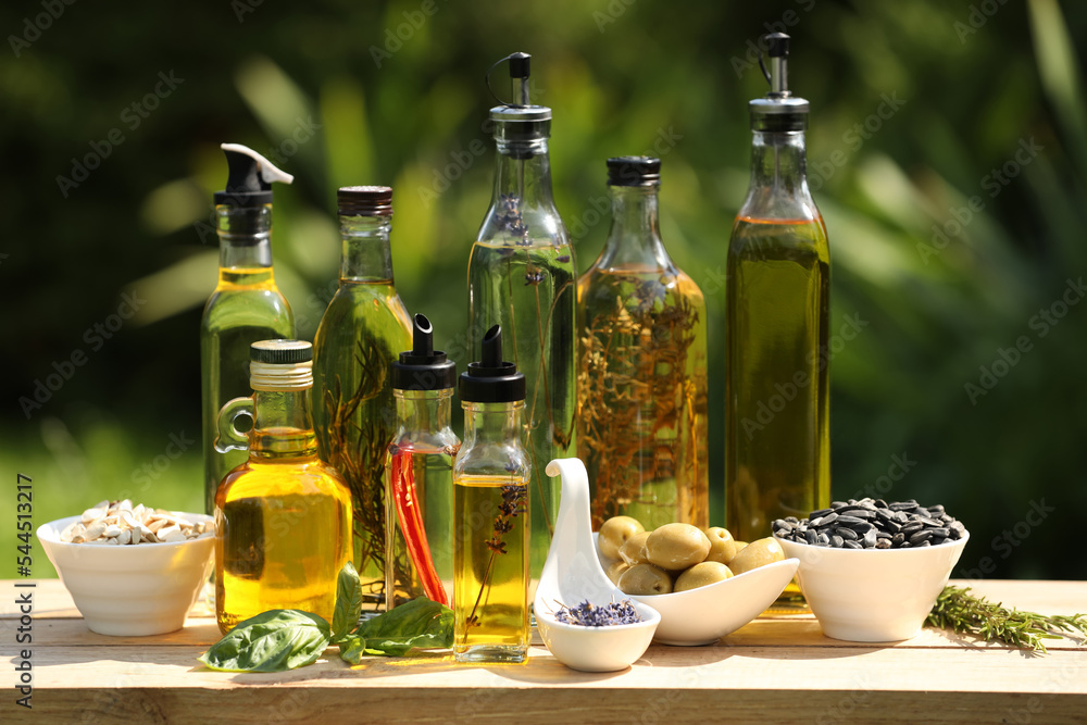Different cooking oils and ingredients on wooden table against blurred green background Different cooking oils and ingredients on wooden table against blurred green background