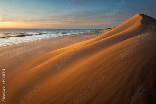 Fotografia A sandy winding path weaves through the sand dunes and towards the sea on the Norfolk Coast at Winterton on Sea as the early morning sun rises above the horizon
