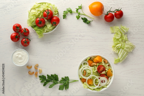 Bowl of delicious salad with Chinese cabbage and different ingredients on white wooden table, flat lay. Space for text