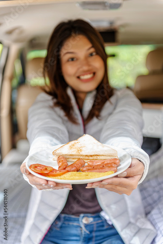 Asian woman showing her breakfast inside the campervan