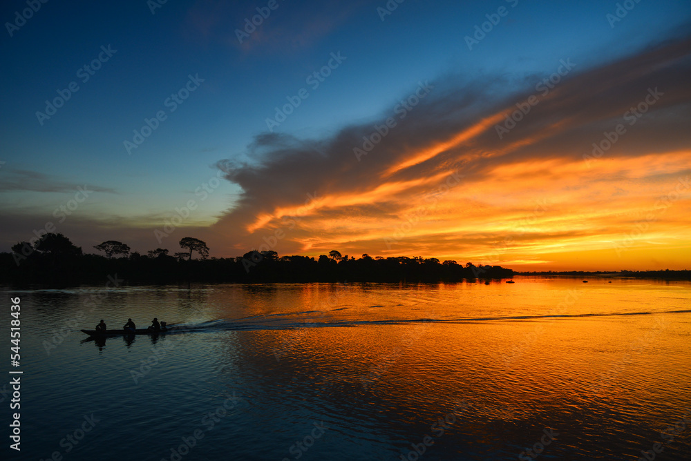 A small motorized canoe during sunset on the Guaporé - Itenez river, Ricardo Franco village, Vale do Guaporé Indigenous Land, Rondonia, Brazil, on the border with Bolivia A small motorized canoe during sunset on the Guaporé - Itenez river, Ricardo Franco village, Vale do Guaporé Indigenous Land, Rondonia, Brazil, on the border with Bolivia