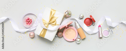 Makeup cosmetics with Christmas decor and gift on light background