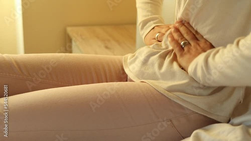young girl presses hard with hands on stomach to relieve period pain, close up shot