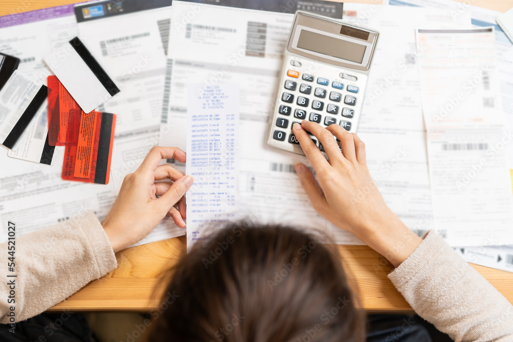 Fototapeta premium Financial owe asian young woman, girl suffer, stressed and confused, hand use calculator calculate expense from invoice or bill, have no money to pay, mortgage or loan. Debt, bankruptcy or bankruptcy.