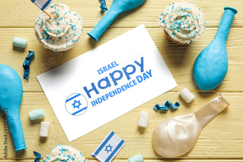 Card with text ISRAEL HAPPY INDEPENDENCE DAY and festive decor on color wooden background, closeup