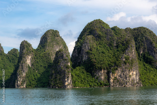 Tropical island limestone mountains, water, and boat view along the ocean sea at Halong Bay in Vietnam