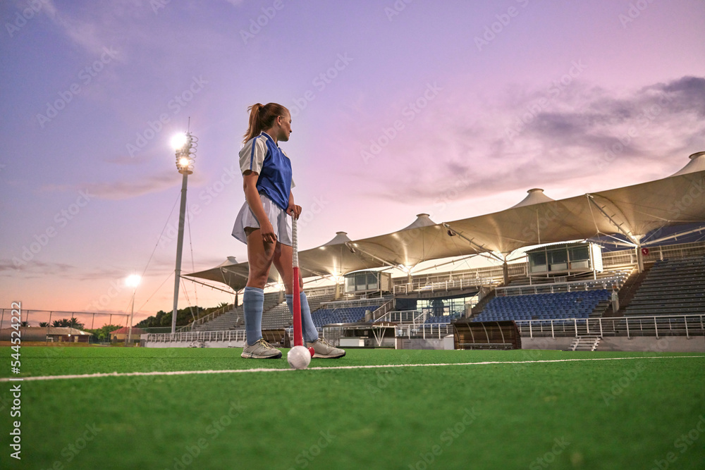 Hockey, stadium and woman sports training, thinking of game strategy and goal fitness health on green pitch field with sunset sky. Young teenager or athlete girl with training gear for competition