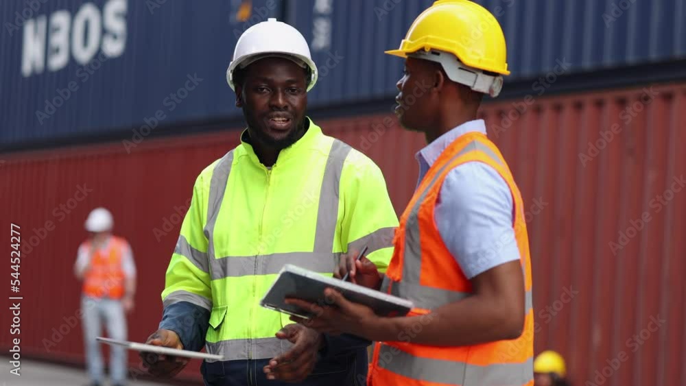 Container import export and logistic concept. Foreman and engineer holding using clipboard and wears PPE to checking inventory or job details with cargo container background. Container import export and logistic concept. Foreman and engineer holding using clipboard and wears PPE to checking inventory or job details with cargo container background.