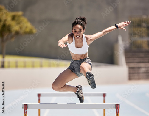 Wall Mural Jump, athlete and hurdle black woman in sports race, competition or training at stadium with energy, power and body challenge