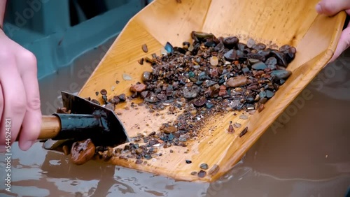 Gold mining at the mines. A man rakes sand from a tray with a pickaxe. Search for gold