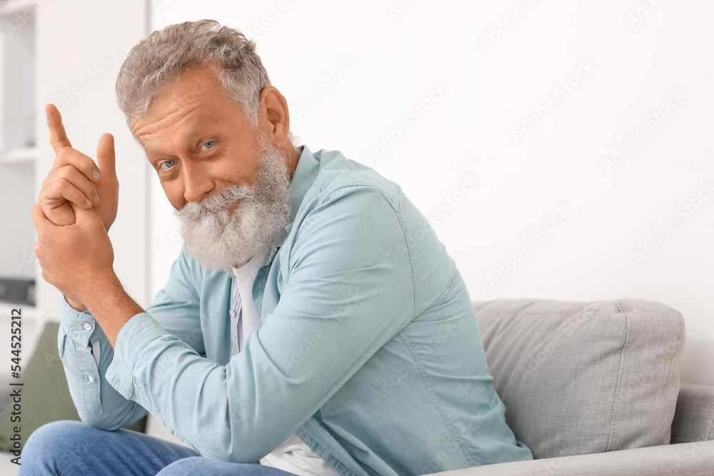 Senior bearded man sitting on sofa at home Senior bearded man sitting on sofa at home