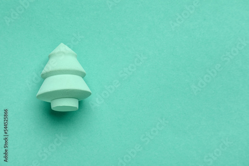 Makeup sponge in shape of Christmas tree on mint background