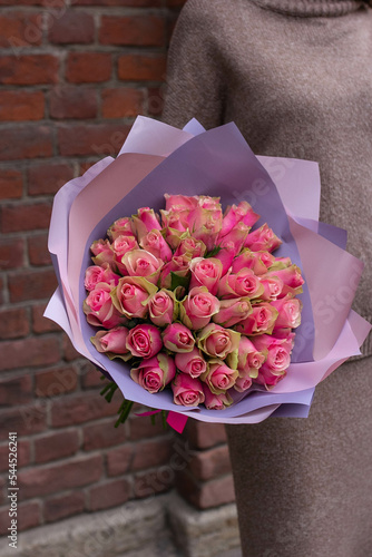 Woman holds in hands bouquet of pink roses