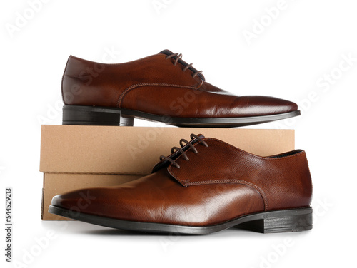 Cardboard box with brown shoes on white background