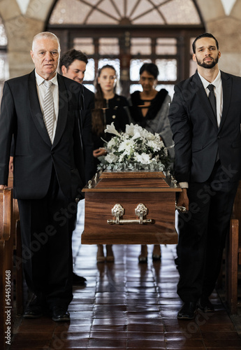Funeral, church and family carry coffin for death, grief or sermon for burial with support. People, pallbearers and sad together with casket for respect, farewell or sorrow in mourning, mass or loss
