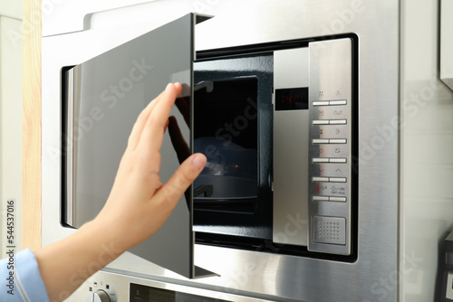 Young woman hand close the modern microwave