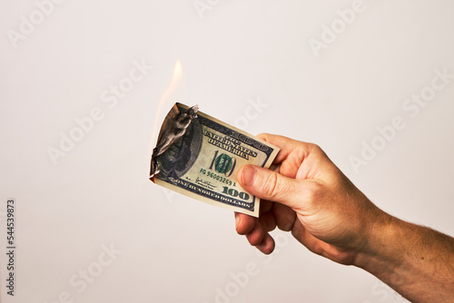 Male hand holding burning dollar money on white background photo