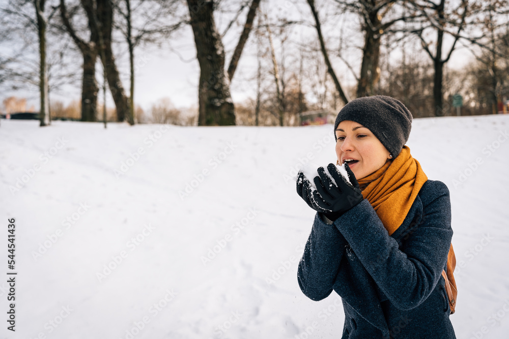A woman blows snow off her palms in winter