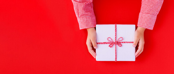banner gift box in children's hands on a red background, presenting a gift