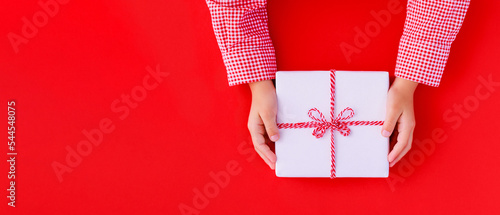 Fotografia banner gift box in children's hands on a red background, presenting a gift