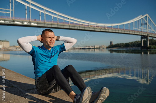Athletic man runner building abs muscles lying on ground