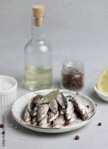 Fresh sardines, salt, oil, lemon and spices on the table, close-up shot. Selective focus. Vertical photo