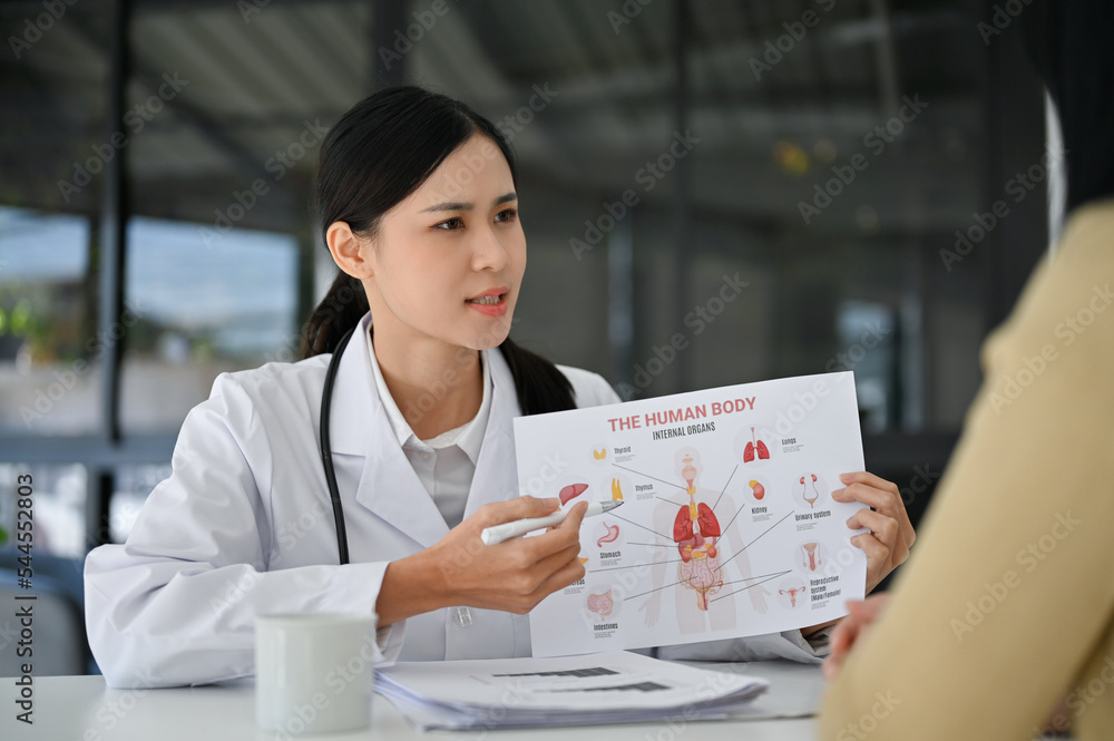 Professional Asian female doctor explaining the human body system to her patient Professional Asian female doctor explaining the human body system to her patient