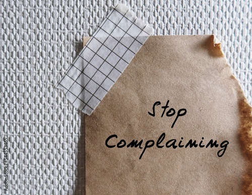 фотографія Torn paper stick on wallpaper with handwriting STOP COMPLAINING, remind oneself