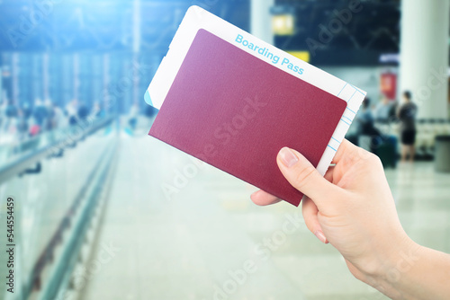 travel visa, flight insurance, international flights, tourism and vacation, hand with passport and boarding pass on the background of the airport photo