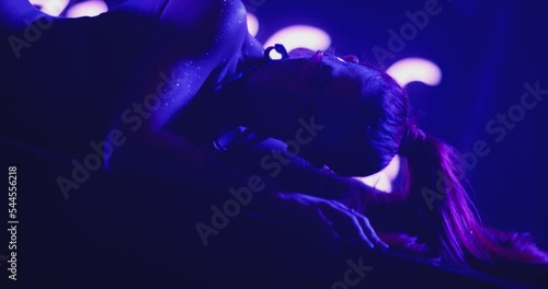 Closeup view of beautiful sexy woman dancing, posing and flirting inside dark place. Sensual scene of female model doing different sexy movements . Female model with g-string and tattoos in strip club