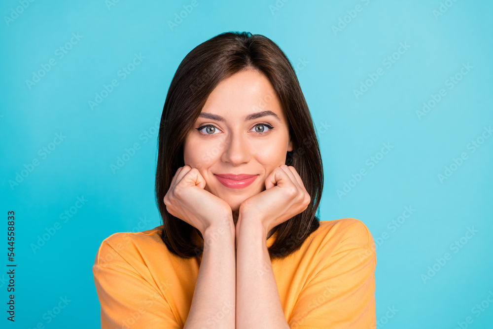 Photo of gorgeous optimistic cute girl with straight hair wear yellow t-shirt arms on cheekbones isolated on blue color background Photo of gorgeous optimistic cute girl with straight hair wear yellow t-shirt arms on cheekbones isolated on blue color background