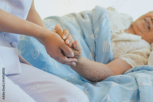 nurse holding hand of senior patient encouraging during cancer treatment
