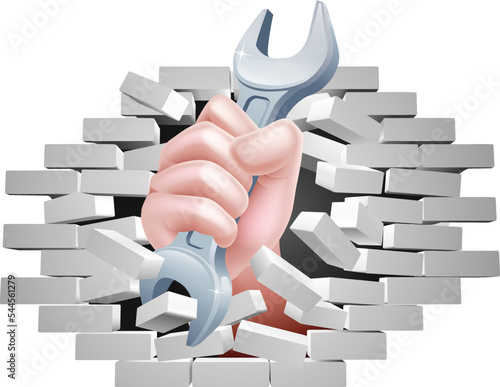 A mechanic fist hand holding a wrench tool spanner breaking through a wall